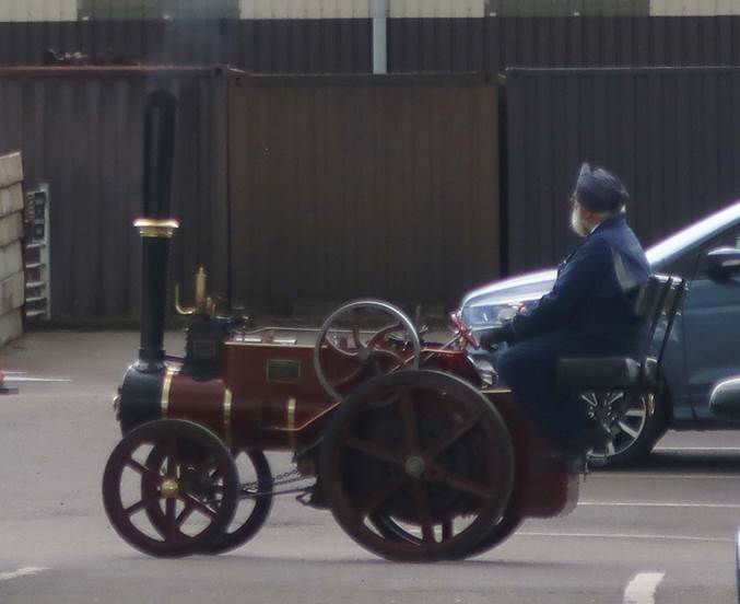 A person in a blue suit sitting on a small steam engine

Description automatically generated