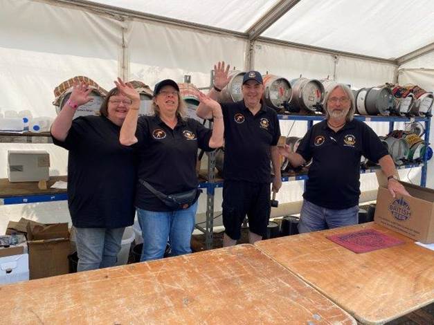 A group of people standing in front of a table with kegs

Description automatically generated with medium confidence