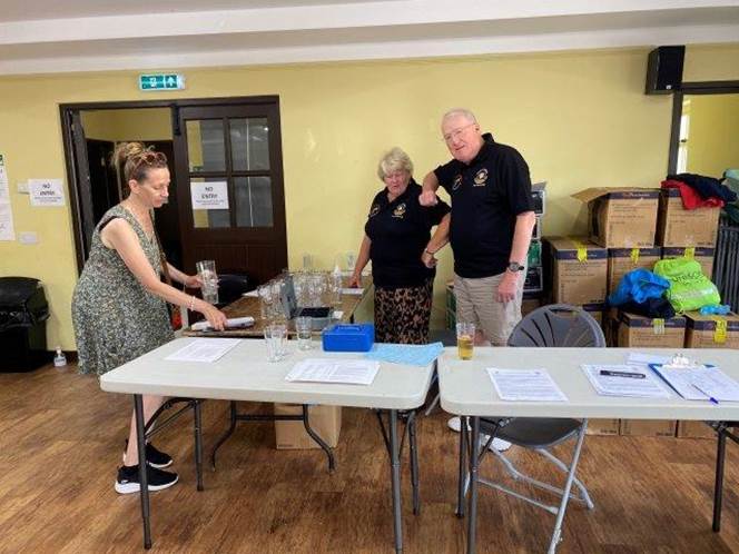 A group of people standing around tables

Description automatically generated with medium confidence
