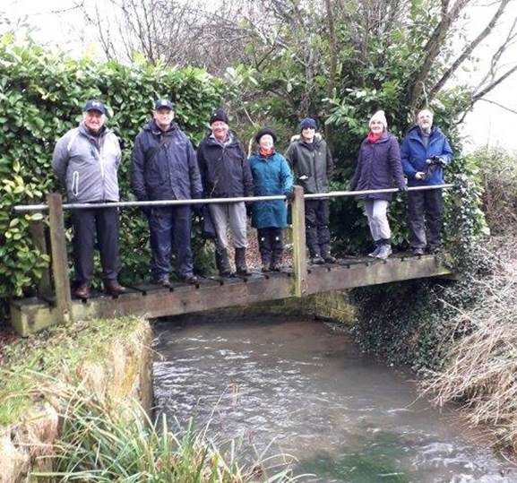 A group of people standing on a bridge over a river

Description automatically generated