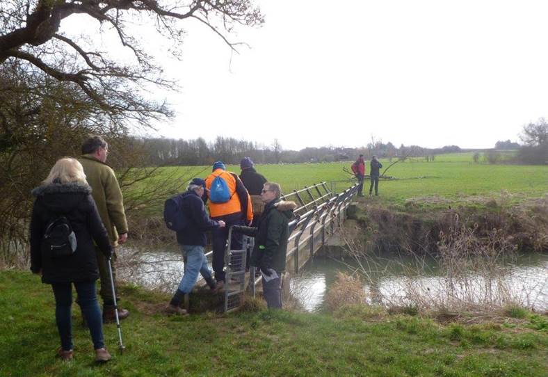 A group of people standing on a bridge over a stream

Description automatically generated with low confidence
